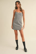 Load image into Gallery viewer, Woman wearing a gray checkered dress on a beige background
